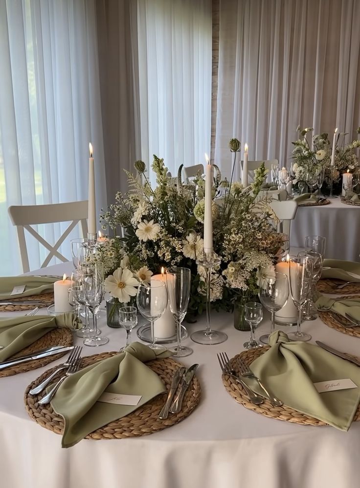 the table is set with silverware, candles and flower centerpieces on it