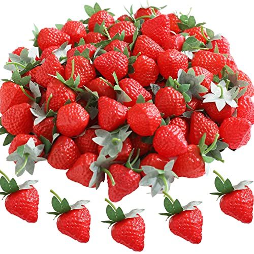 a pile of red strawberries with leaves on them