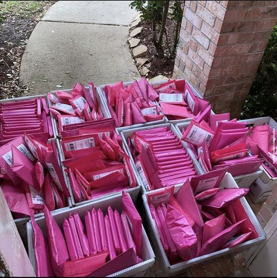 many pink boxes are stacked on top of each other in front of a brick building