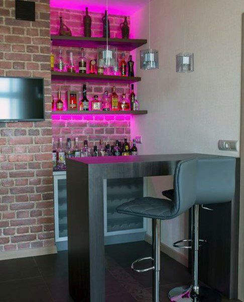 a bar with two stools in front of it and bottles on the shelves behind it