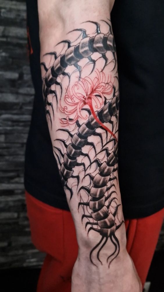 a man with a tattoo on his arm and hand is holding a red flower in the shape of a dragon