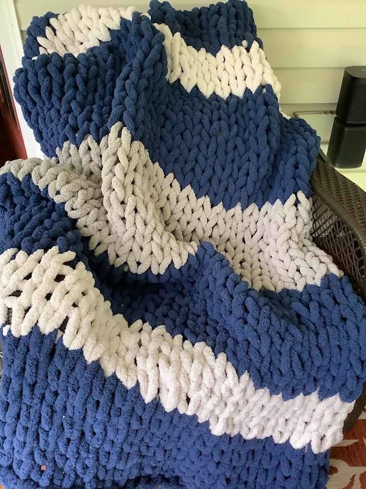 a blue and white blanket sitting on top of a wooden floor next to a chair