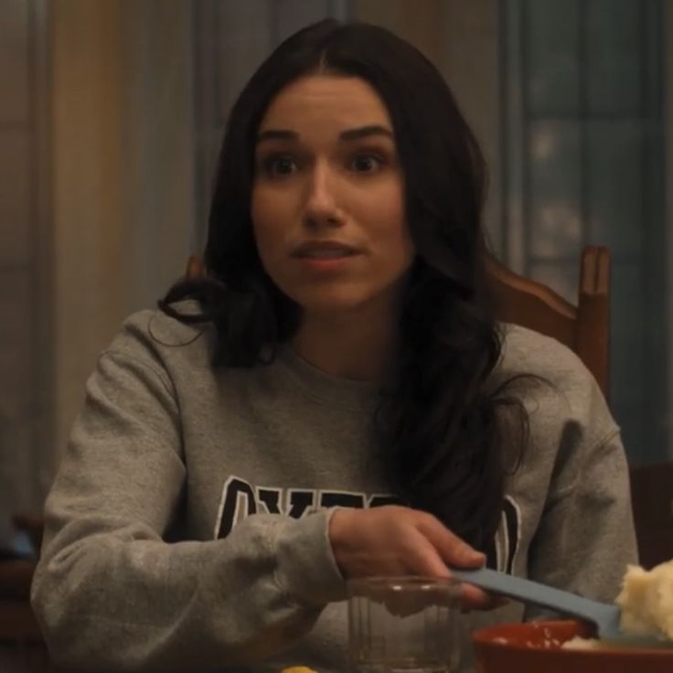 a woman sitting at a table with food in front of her and looking to the side