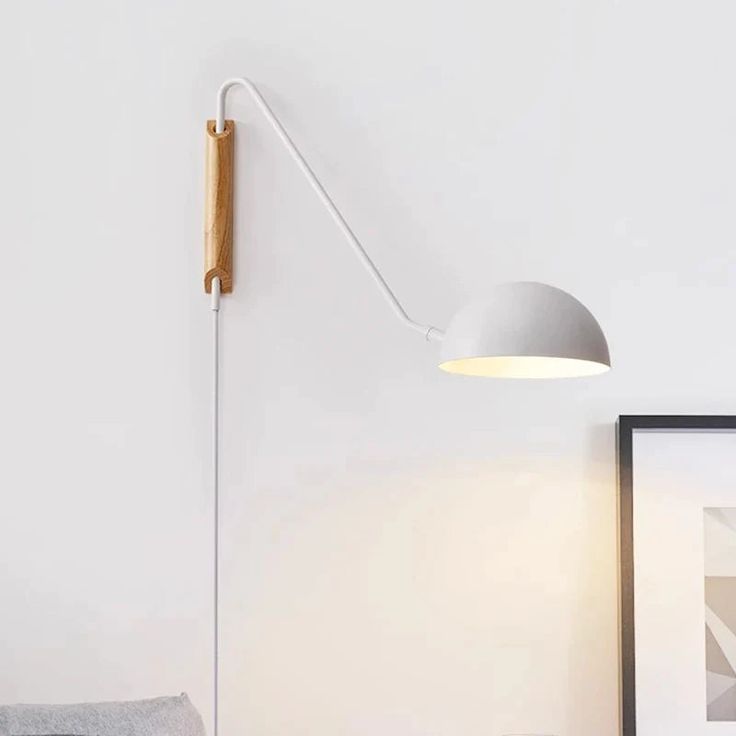 a white lamp on the wall next to a bed