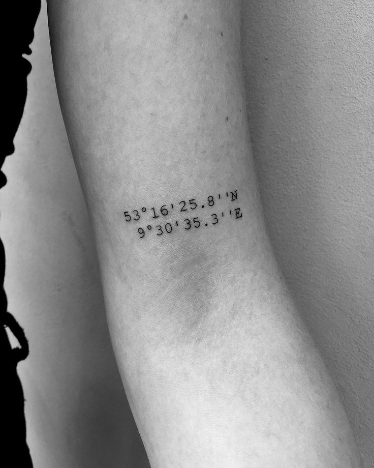 a woman's arm with the coordinates tattoo on her left forearm and numbers in black ink