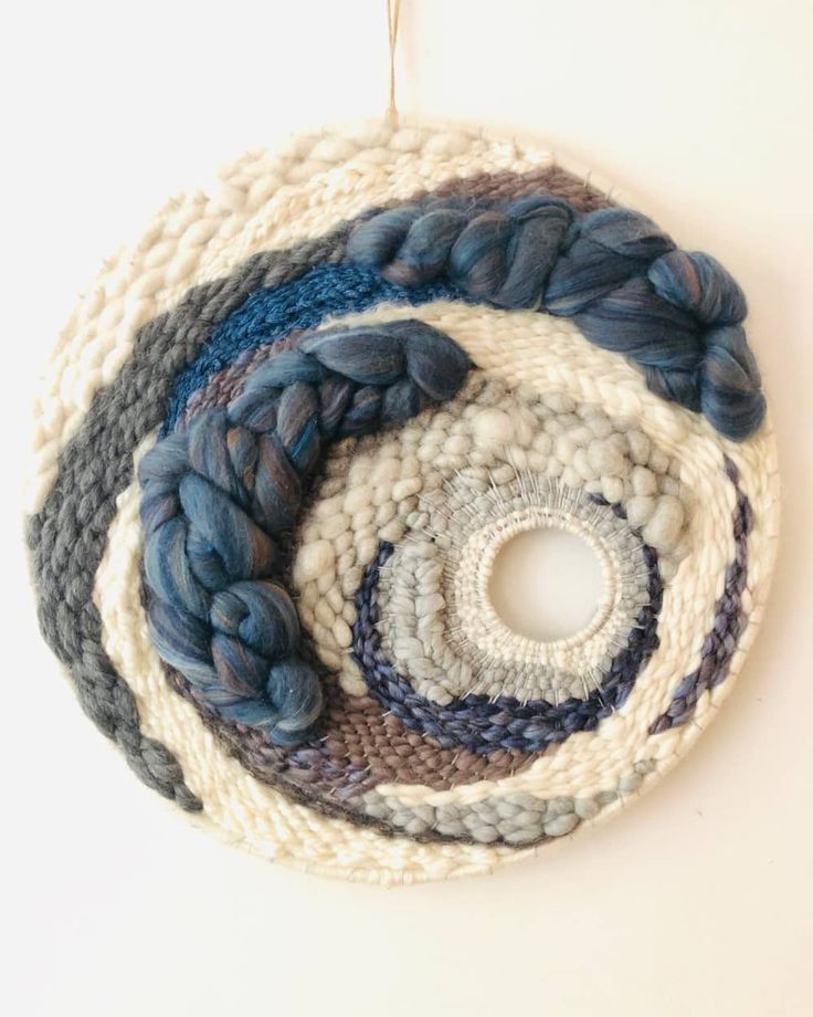 a crocheted circular ornament hanging from a hook on a white wall