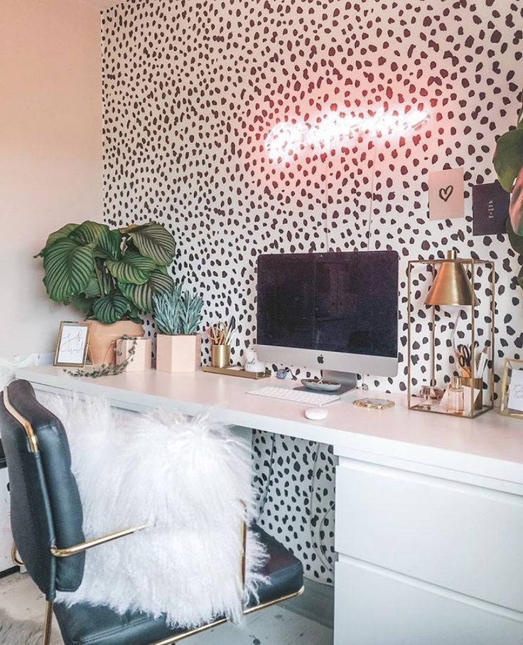 a white desk topped with a computer monitor next to a plant