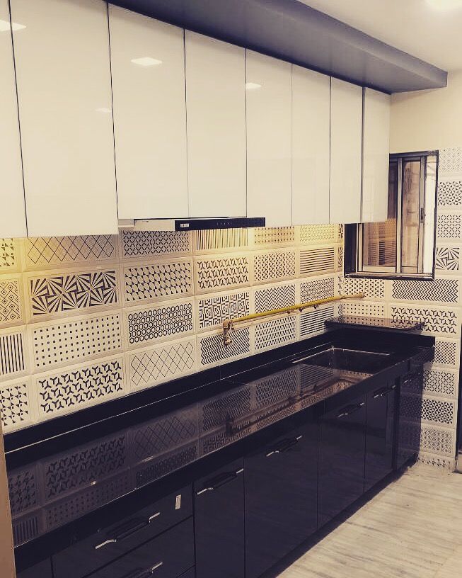 a kitchen with white cabinets and black counter tops in front of a mirror on the wall