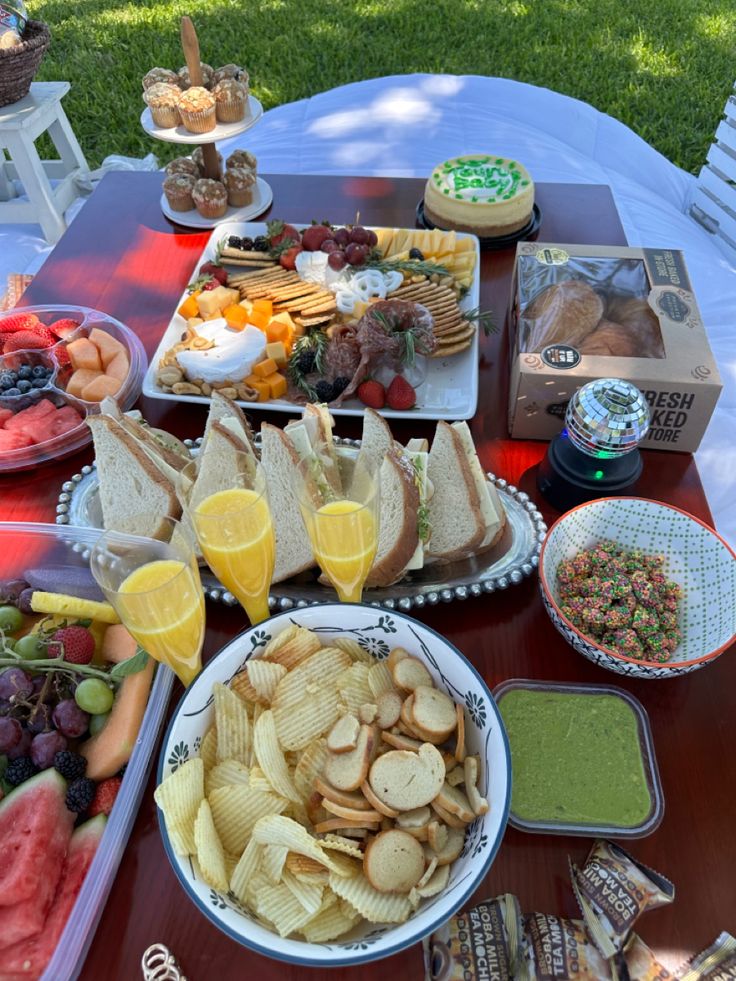 a table full of food and drinks on it's outdoor dining area with grass in the background