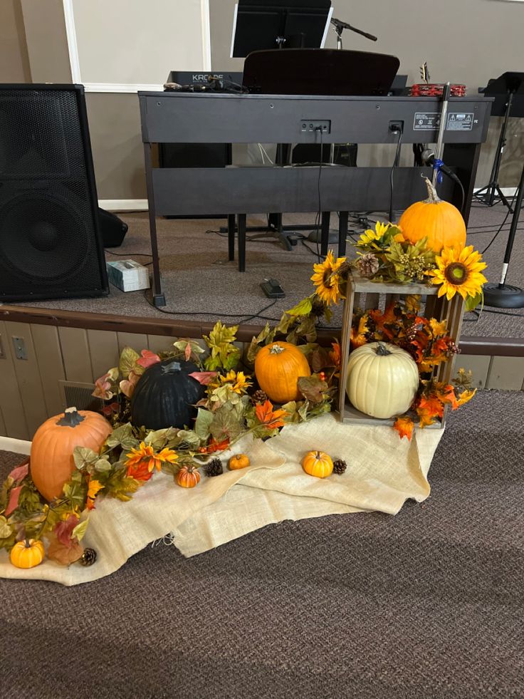 an arrangement of pumpkins and sunflowers on a table in front of a piano