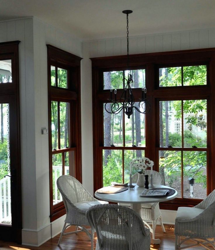 there is a table and chairs in the room with large windows that look out onto the woods