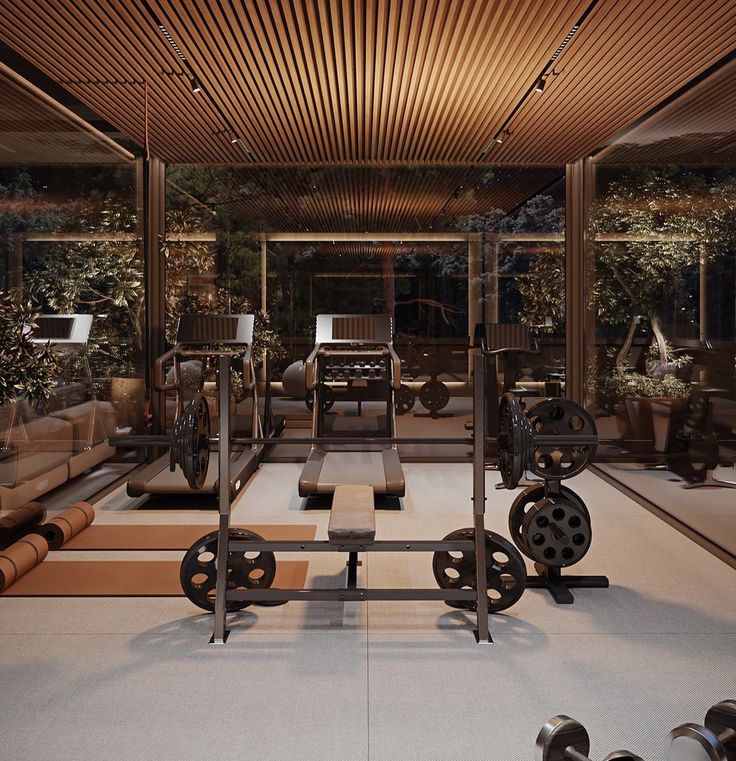 an indoor gym with exercise equipment in the center and large windows to the outside area