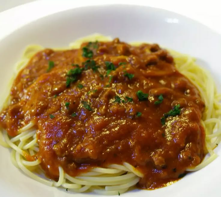 a white bowl filled with spaghetti and sauce