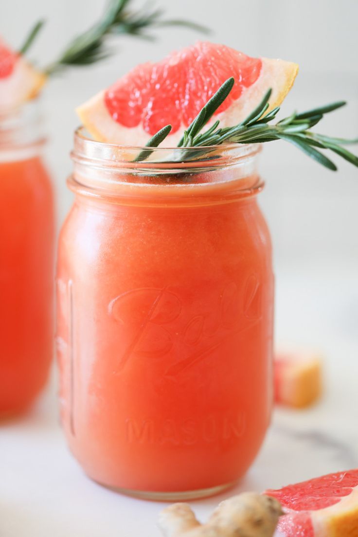 grapefruit and orange juice in mason jars with rosemary sprigs