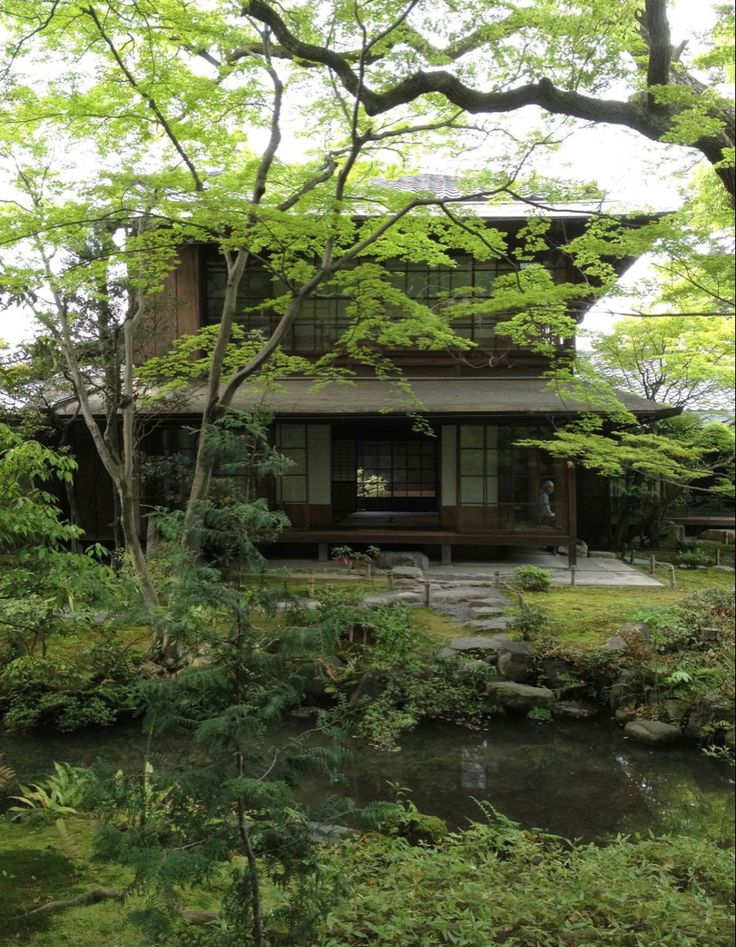 a small house sitting next to a river in the middle of a lush green forest