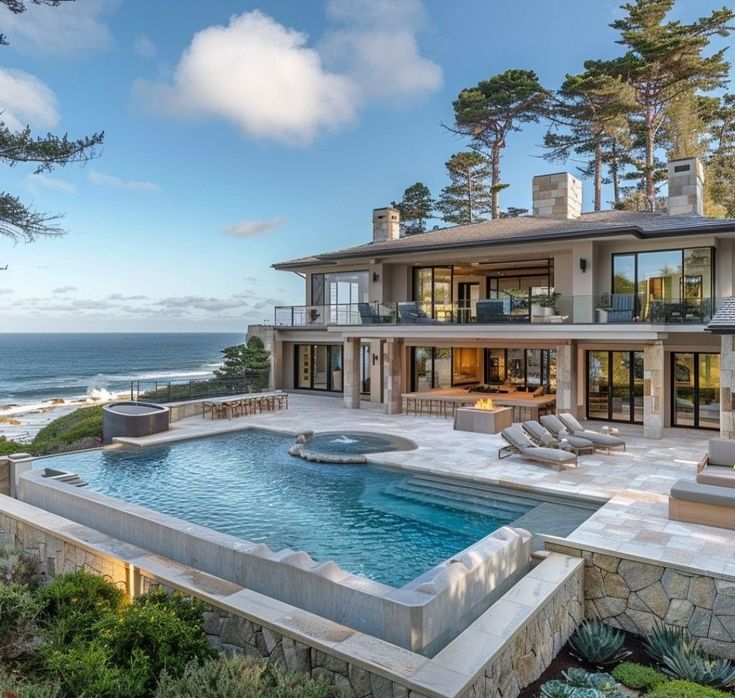 a large house with a swimming pool in front of it and the ocean behind it