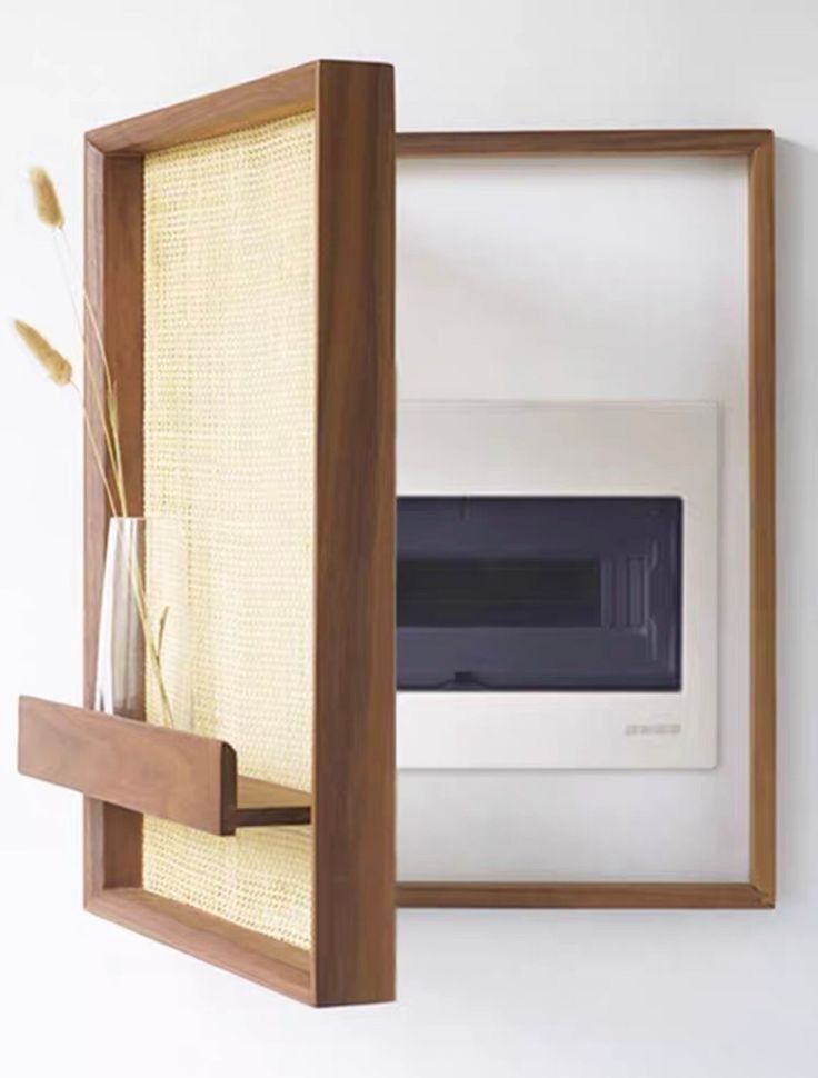 a wall mounted oven in a wooden frame with a vase on the shelf next to it