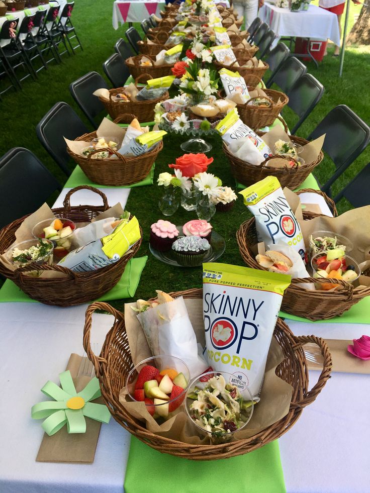 a table topped with baskets filled with food next to tables covered in green cloths