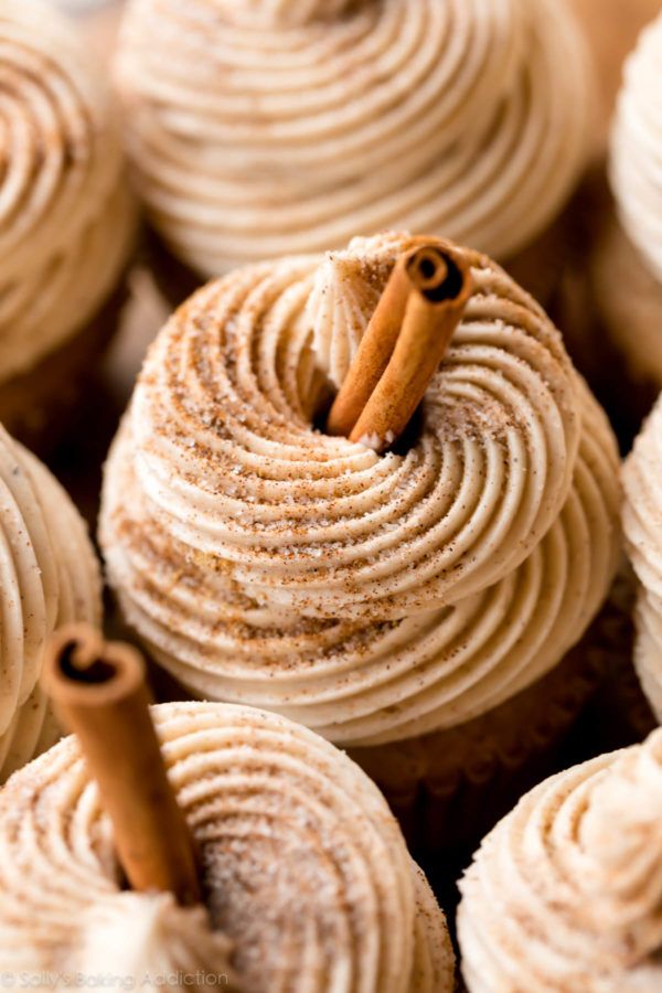 cinnamon roll cupcakes with cinnamon stick sticking out of the top and frosting