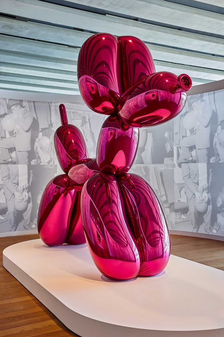 a pink balloon dog sitting on top of a white platform