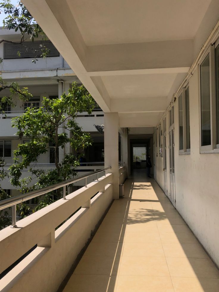 an empty walkway between two buildings with trees in the background