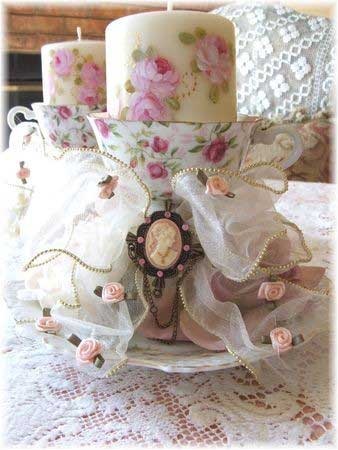 a table topped with two candles and a plate covered in fabric flowers on top of a lace doily