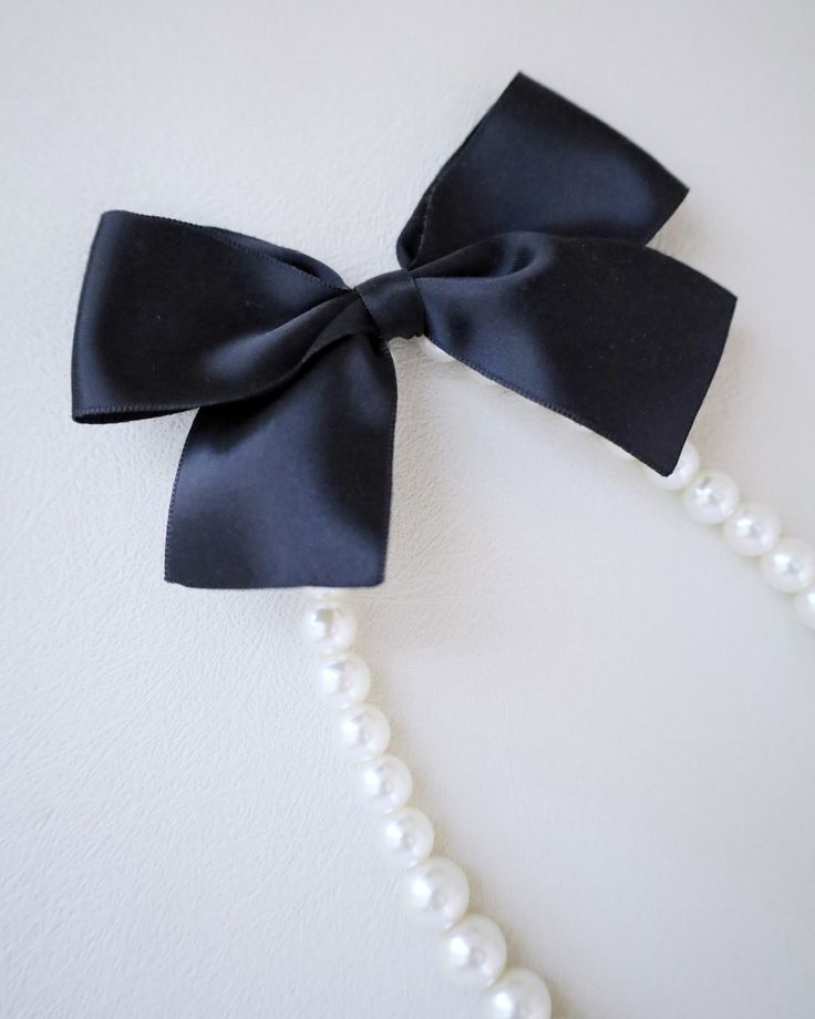 A classic pearl necklace with a dainty satin bow definitely to add an effortless romantic and classic look to your formal or casual style. Perfect to complete your date night, wedding, bridesmaids, holiday party, and any special occasions. This necklace is elastic and consists of assorted sizes of pearls. The bow can be styled sideways or at the back, or turn it around for another way to wear it. DETAILS: HANDMADEIMPORTED MATERIALS Feminine Bow Necklace For Party, Elegant Bow Necklace For Party, Elegant Party Necklace With Bow, Classic Adjustable Necklaces For Party, Elegant Black Pearl Necklace For Weddings, Elegant Ribbon Necklaces For Evening, Classic Adjustable Pearl Necklace For Party, Elegant Black Ribbon Jewelry For Gift, Elegant Adjustable Pearl Necklace For Formal Occasions