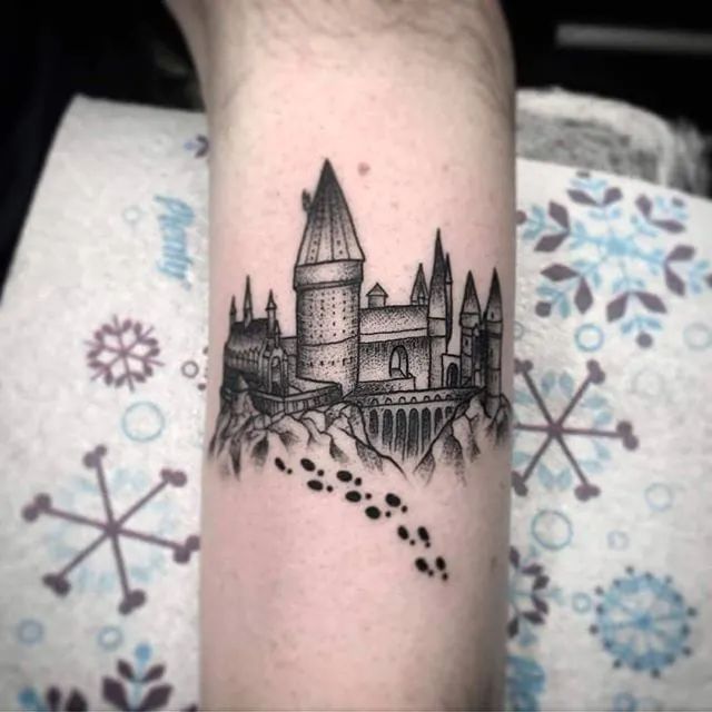 a black and white photo of a castle tattoo on the arm