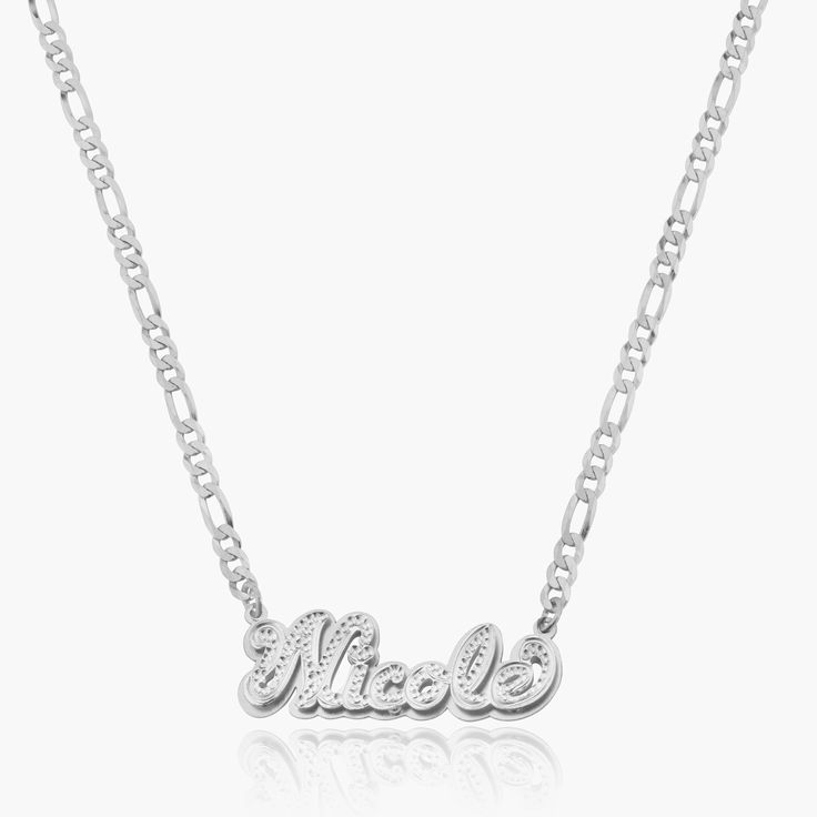 Our popular Double Plated Iced Out Script Name Necklace boasts a chic and elegant design, handcrafted to perfection. The model showcases the necklace with an 18-inch Cuban chain (see image for reference). Chain width:Cuban Chain - 3.7 mmFigaro Chain - 3 mmRope Chain - 2.3 mm Closure: All chains are fitted with a lobster clasp. Metal Selection: Gold Plated Silver Plated Sterling silver 14k gold plated over sterling silver 14k solid gold - (NAMEPLATE ONLY) Curb Chain Pendant Necklace, Anniversary Silver Name Necklace With Figaro Chain, Elegant Personalized Link Necklaces, White Gold Necklace With Figaro Chain Link, White Gold Pendant Necklace With Curb Chain, Figaro Chain Nameplate Jewelry For Anniversary, Elegant Name Necklace With Figaro Chain For Anniversary, Elegant Figaro Chain Name Necklace For Anniversary, Elegant Silver Charm Necklace With Curb Chain