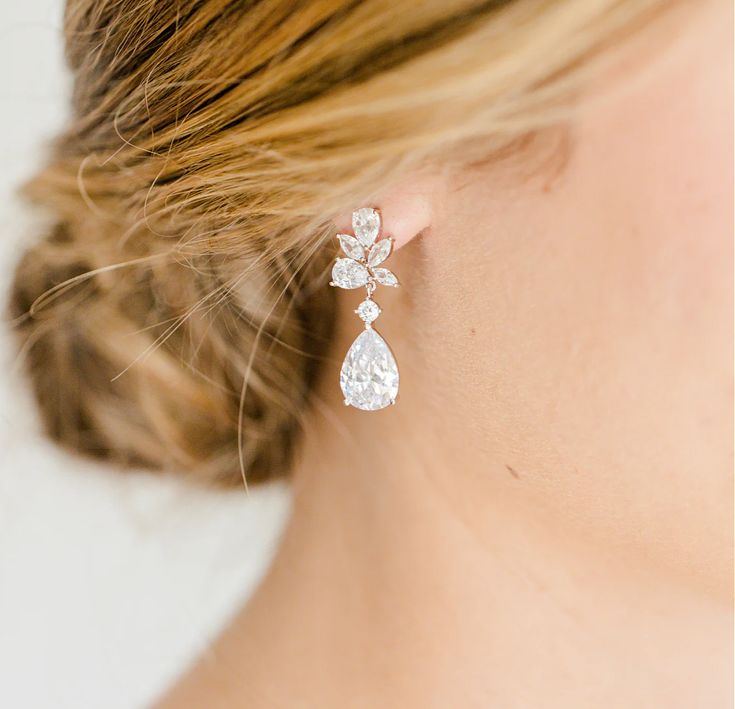 a close up of a woman's ear wearing a pair of white diamond earrings