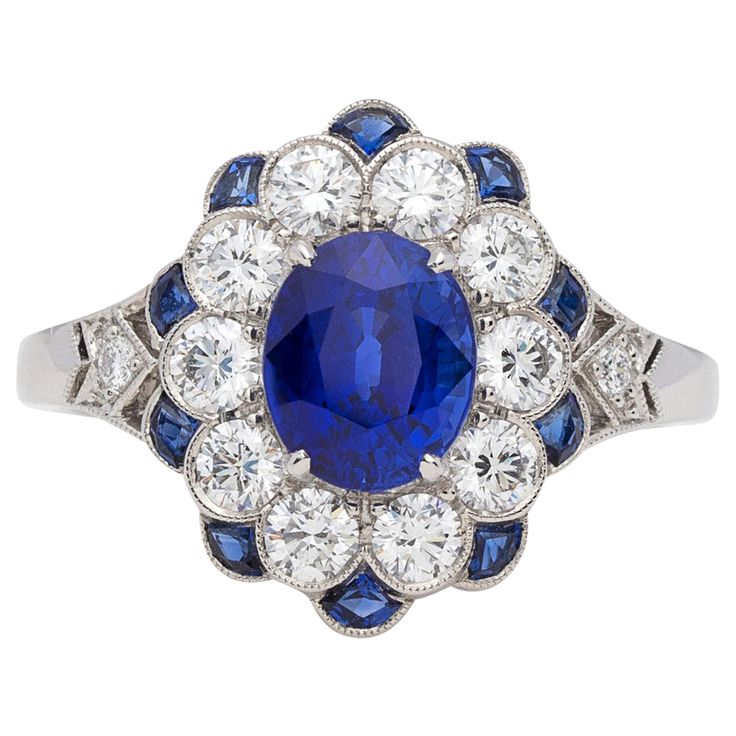 A beautiful update on the classic Lady Diana ring, this platinum Art Deco inspired ring centers an oval-shaped sapphire weighing approximately 1.65 carats, with well saturated, deep blue color, surrounded by sparkling round brilliant-cut diamonds and calibre-cut sapphires. The sapphire weigh totals 2.05 carats, and the diamond weight is 0.71ct. Elegant, eye-catching and exceptionally well made. 1 5 Carat Engagement Ring, 5 Carat Engagement Ring, Diana Ring, Wedding Rings Art, Art Deco Sapphire Ring, Diamond Sapphire Engagement Ring, Sapphire Diamond Engagement, Vintage Engagement Rings Sapphire, Blue Engagement Ring