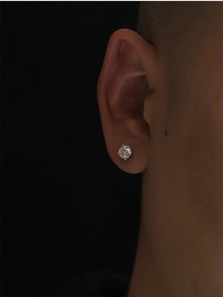 a close up of a person wearing a pair of ear piercings with a single diamond in the middle