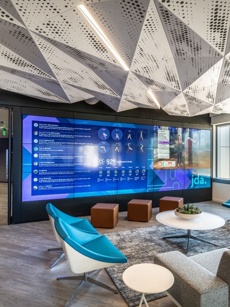 an office lobby with chairs, tables and large screen