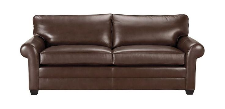 a brown leather loveseat sitting on top of a white floor next to a gray wall