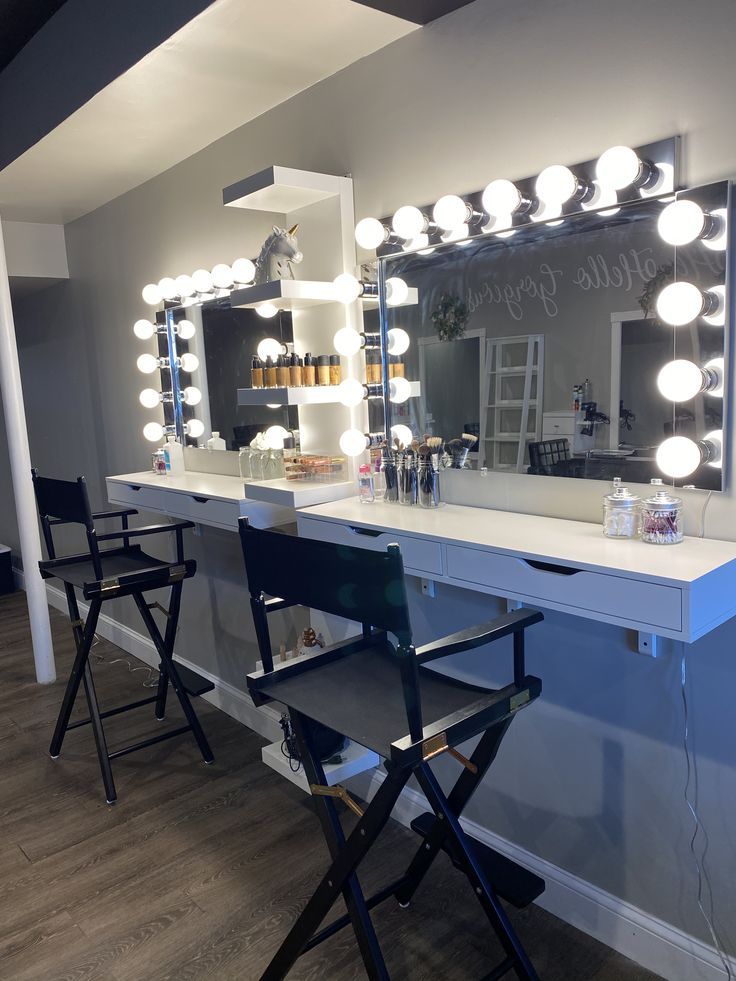 a vanity with lights and stools in front of it