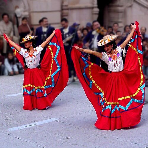 two women in red dresses are dancing on the street