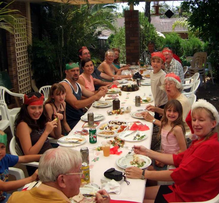 a group of people sitting around a table with plates of food and drinks in front of them