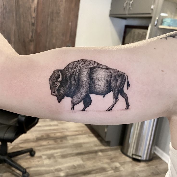 a bison tattoo on the left arm