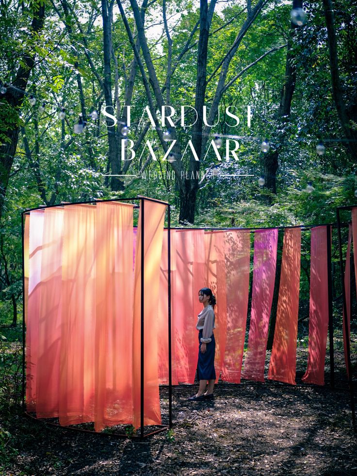 a person standing in front of some red and pink structures with trees behind them,