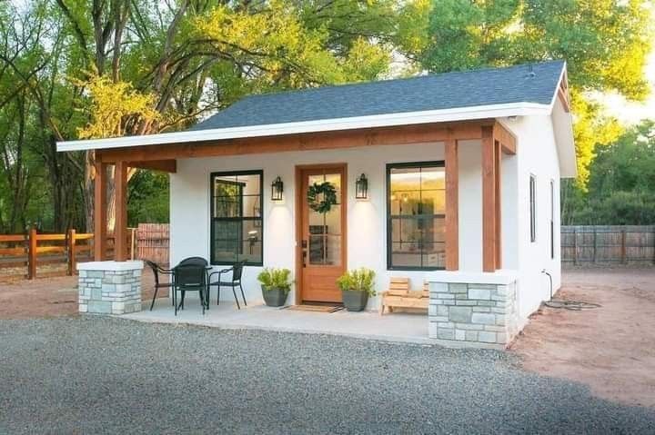 a small white house sitting on top of a gravel lot