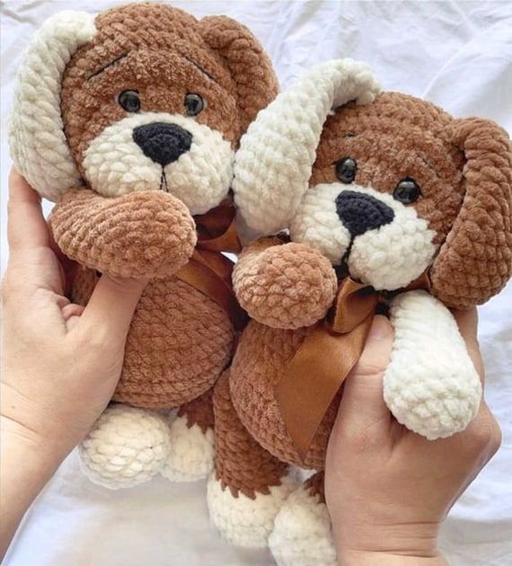 two brown and white stuffed animals being held by someone