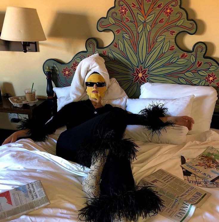 a person in a mask laying on top of a bed with pillows and blankets around them