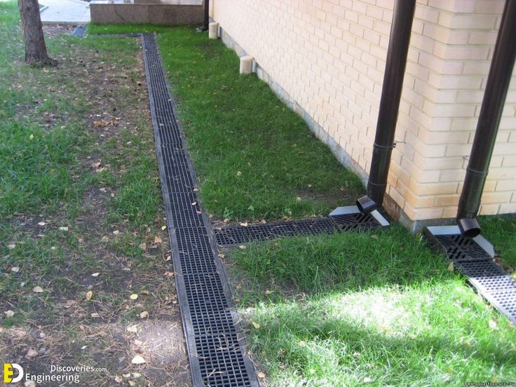 a black grate in the grass next to a building