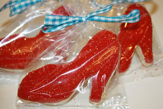 two red shoe shaped cookies wrapped in plastic on a white counter top with blue ribbon