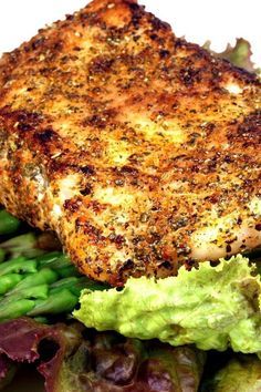 a white plate topped with meat and veggies next to broccoli covered in seasoning