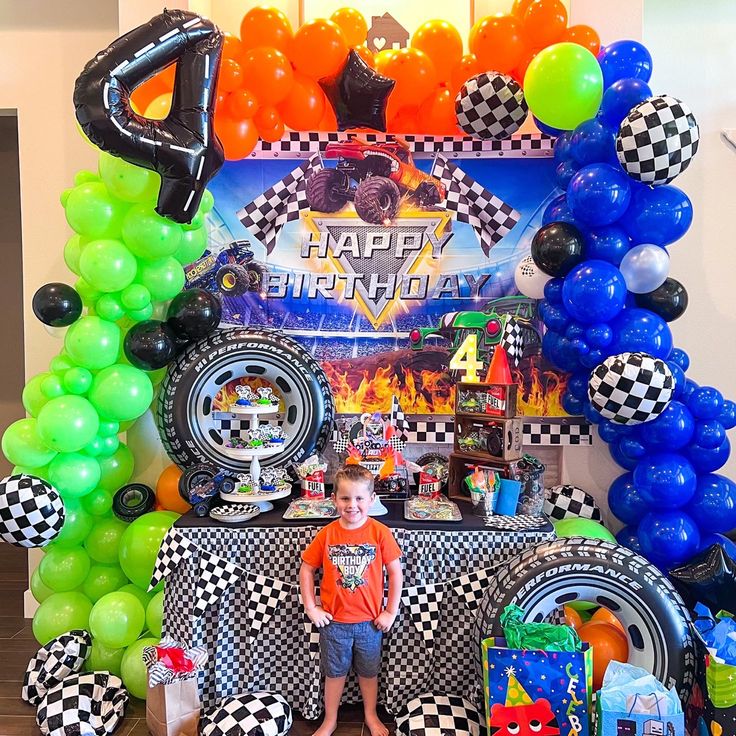 a boy standing in front of a birthday cake table with balloons and decorations on it