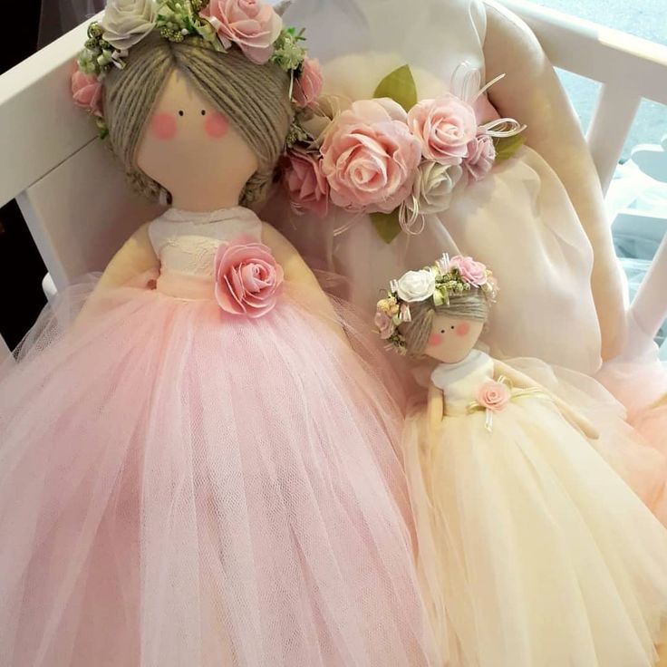 two dolls are dressed in pink and yellow tulle skirts with flowers on their heads