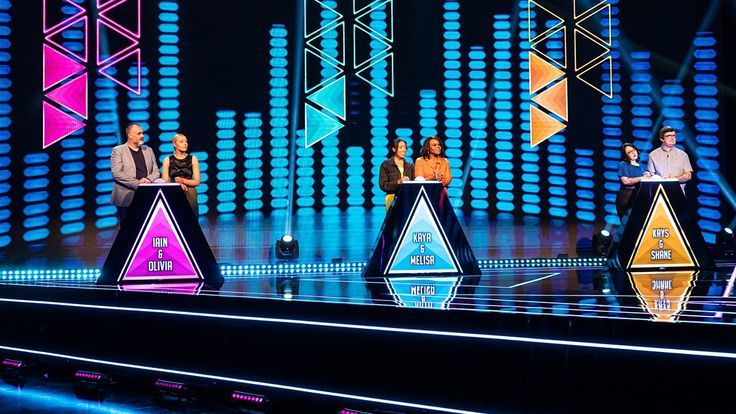 the contestants are standing on stage in front of colorful lights