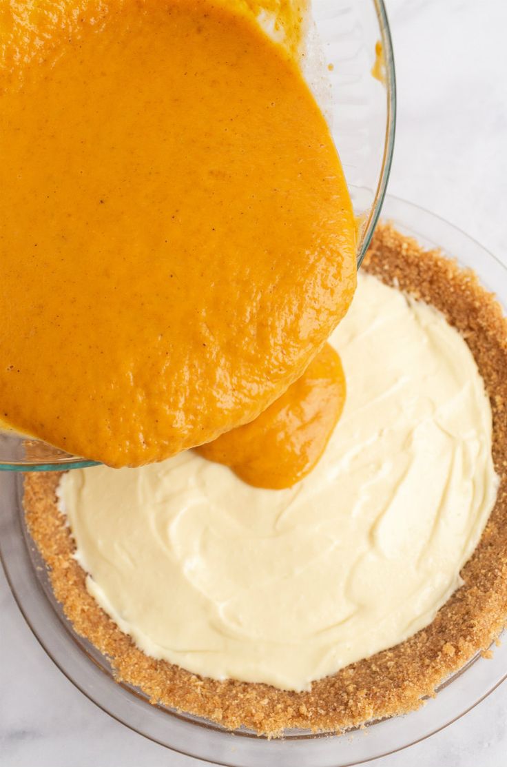 someone is spreading icing on the top of a pie crust in a glass bowl