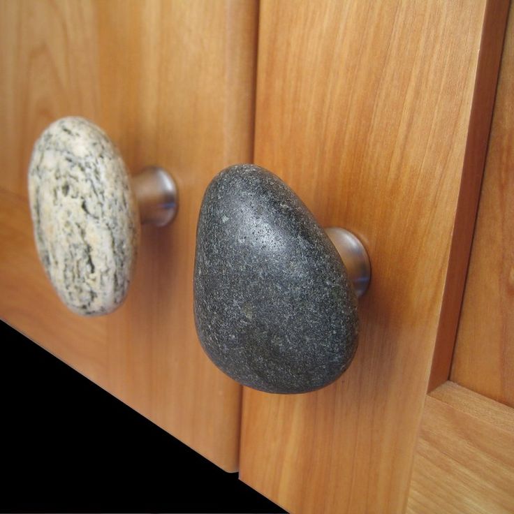 two rocks are on the door handle of a wooden cabinet, one is black and one is white